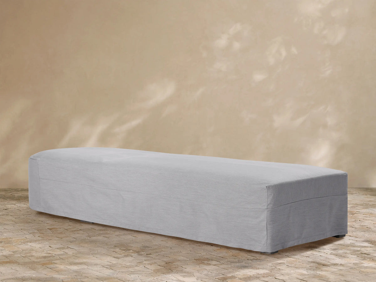 Light grey Bal Harbour outdoor collection covers on a sofa, chaise, and armchair outdoors on a stone patio.