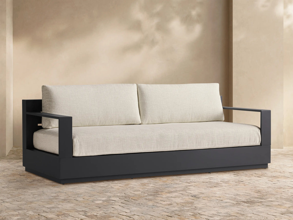 Front view of the Bal Harbour Outdoor Aluminum Sofa with dark charcoal aluminum frame and light linen cushions, styled with accent pillows and a throw.