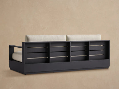 Angled close-up of Bal Harbour Outdoor Aluminum Sofa. Dark charcoal frame, light beige textured seat & back cushions.