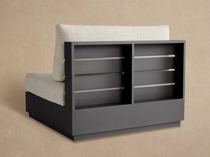 Close-up of Bal Harbour armless chair. Dark gray aluminum frame with horizontal gaps, light beige textured cushion on top.