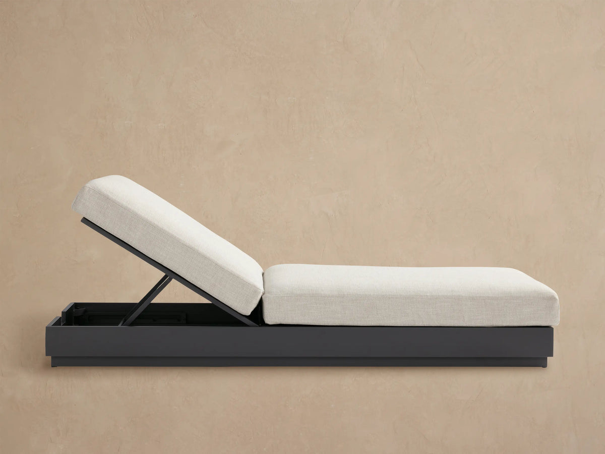 Bal Harbour Outdoor Aluminum Chaise with dark gray base and light beige cushion, raised backrest, on a tiled patio.