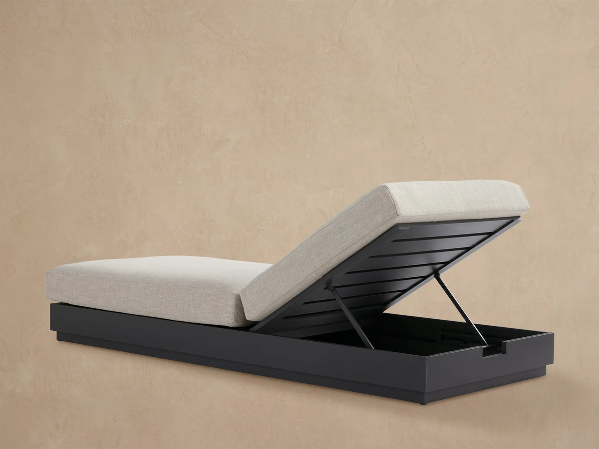 Close-up of Bal Harbour Outdoor Aluminum Chaise's dark gray adjustable backrest with slats, supporting a light beige textured cushion.