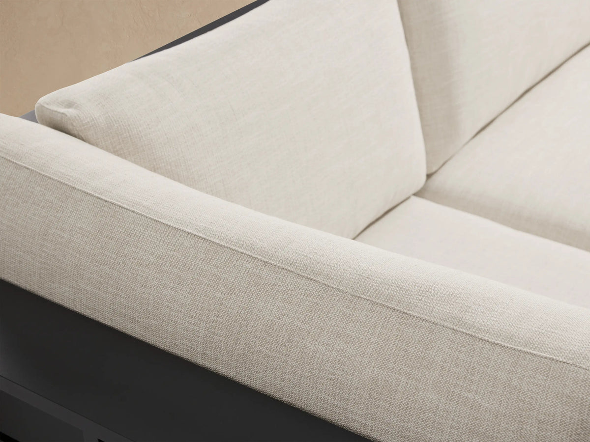 Bal Harbour L-shaped outdoor sectional with dark aluminum frame and light cream cushions on a stone patio.