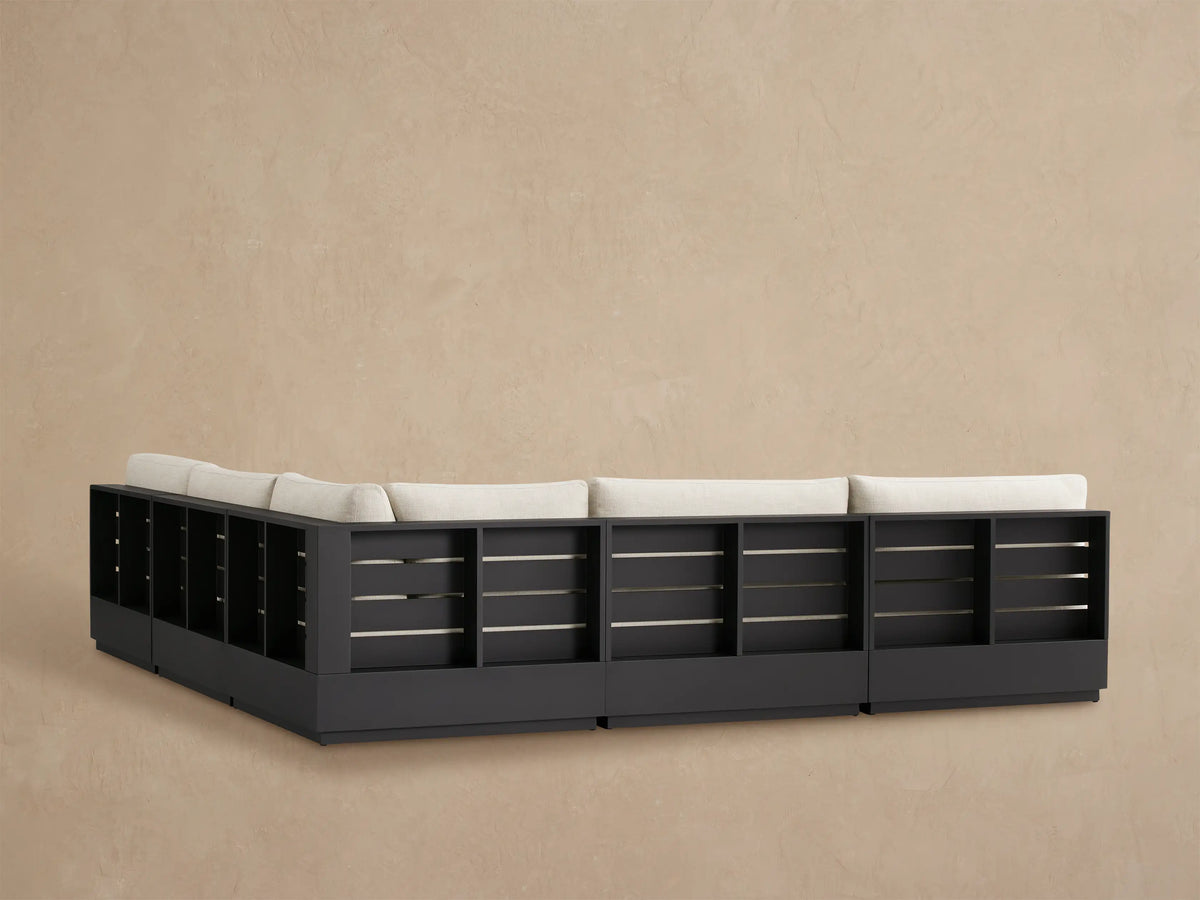 Close-up of Bal Harbour Outdoor Sectional armrest and cushions in light beige fabric with a dark aluminum frame.