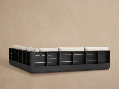 Close-up of Bal Harbour Outdoor Sectional armrest and cushions in light beige fabric with a dark aluminum frame.