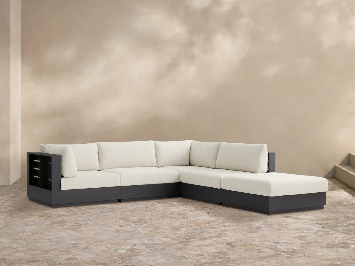 Bal Harbour Outdoor L-shaped sectional with ottoman. Dark gray aluminum frame, light cream cushions on a patterned patio floor.