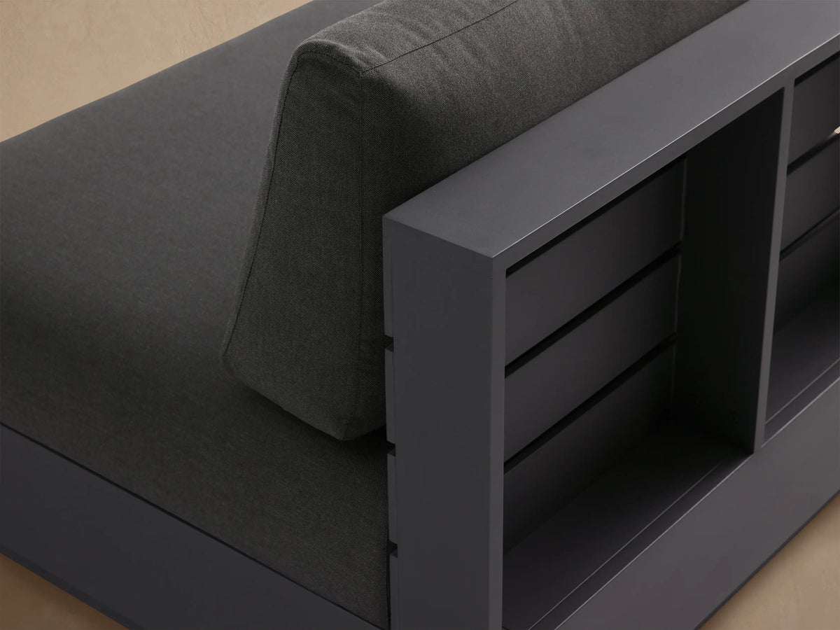 Bal Harbour Outdoor Aluminum Armless Chair, dark gray, with thick seat and back cushions, on a stone patio.