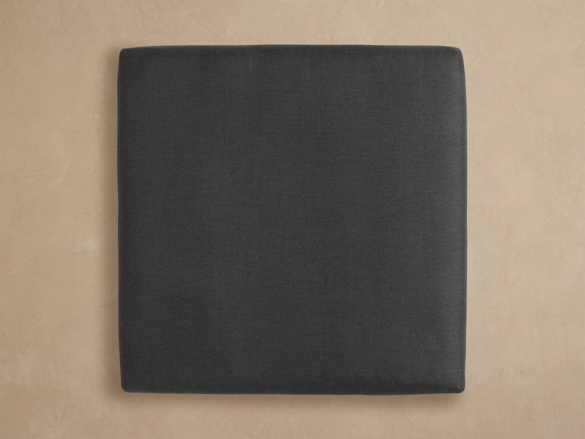 Close-up of Bal Harbour Outdoor Aluminum Ottoman, dark grey fabric cushion resting on a black rectangular aluminum frame, angled view.