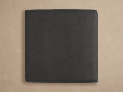 Close-up of Bal Harbour Outdoor Aluminum Ottoman, dark grey fabric cushion resting on a black rectangular aluminum frame, angled view.