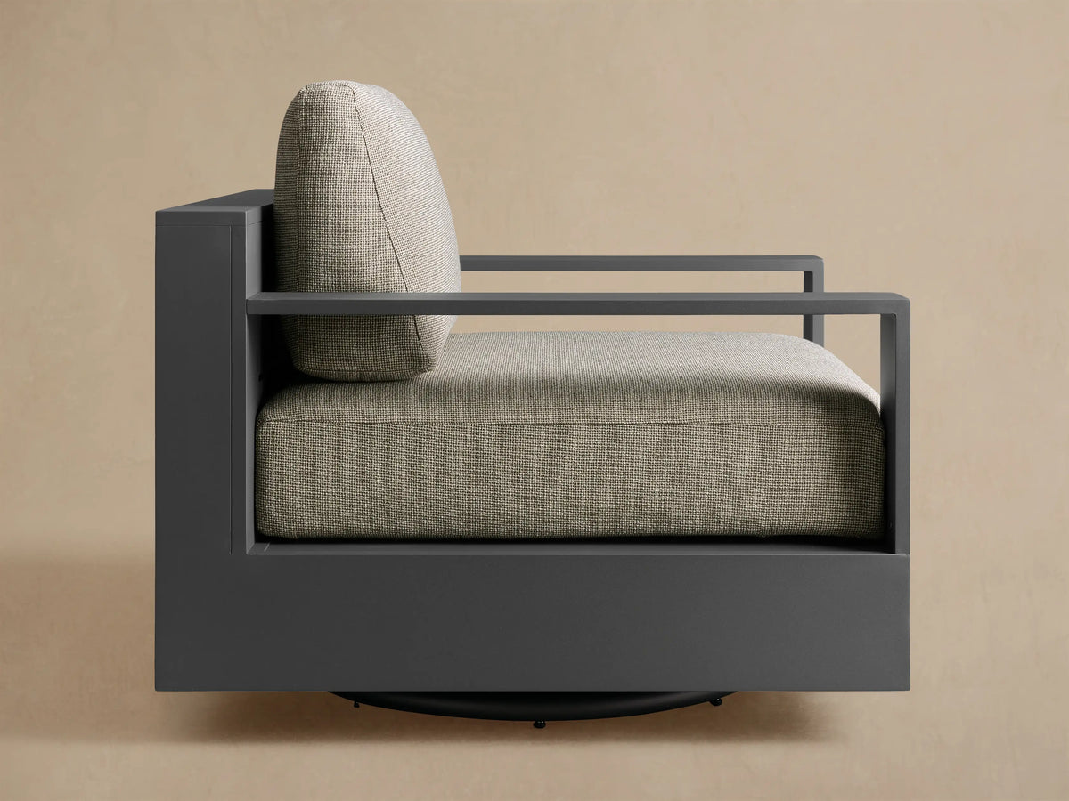 Rear-quarter view of the Bal Harbour Outdoor Aluminum Swivel Chair with dark gray slatted aluminum frame and light gray cushions.