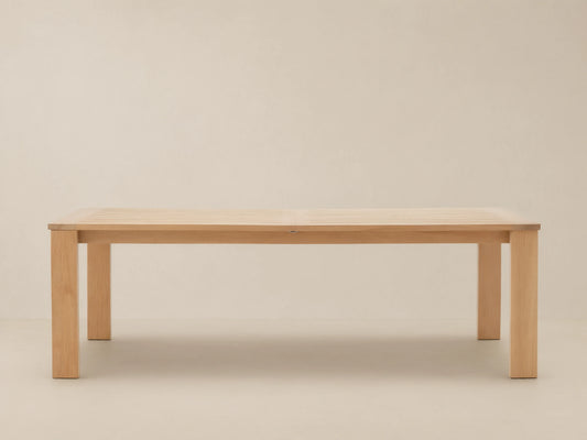 Bal Harbour Outdoor Teak Extension Dining Table, light teak wood with slatted top and sturdy legs, on a stone patio.