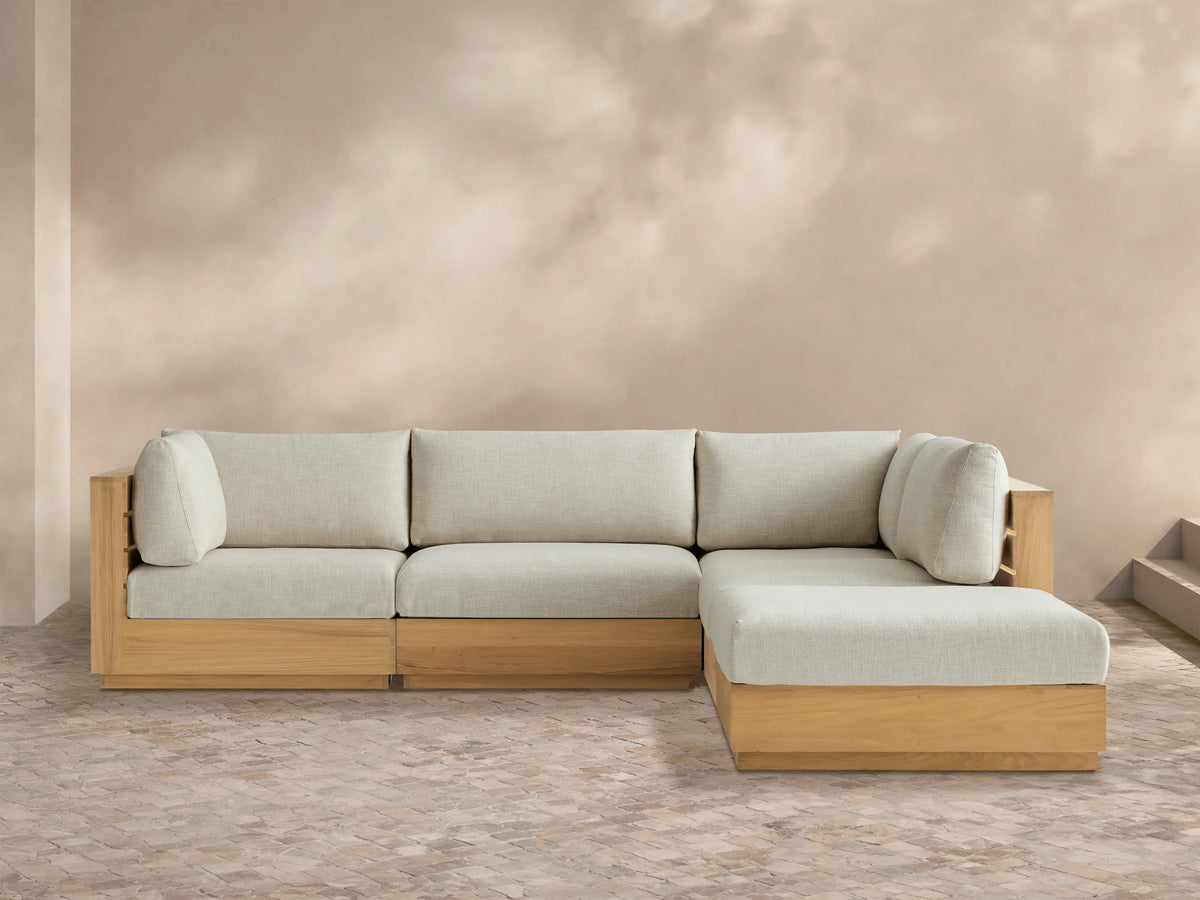 Bal Harbour Outdoor Teak Five-Piece Sectional with Ottoman, light teak frame & light beige cushions in L-shape on tiled patio.