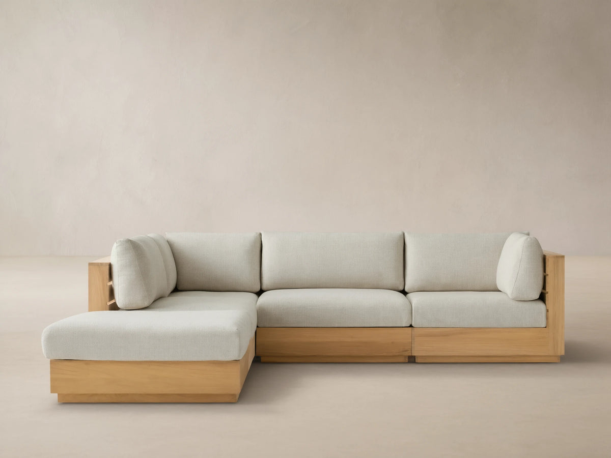 Bal Harbour Outdoor Teak Five-Piece Sectional with Ottoman, light teak frame & light beige cushions in L-shape on tiled patio.