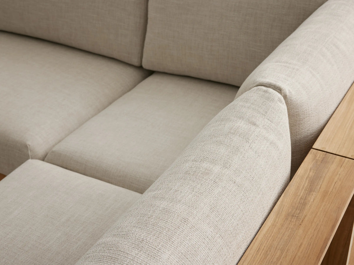 U-shaped Bal Harbour Teak 6-piece sectional with natural wood frame, open left arm shelf, & light cushions on a patio.