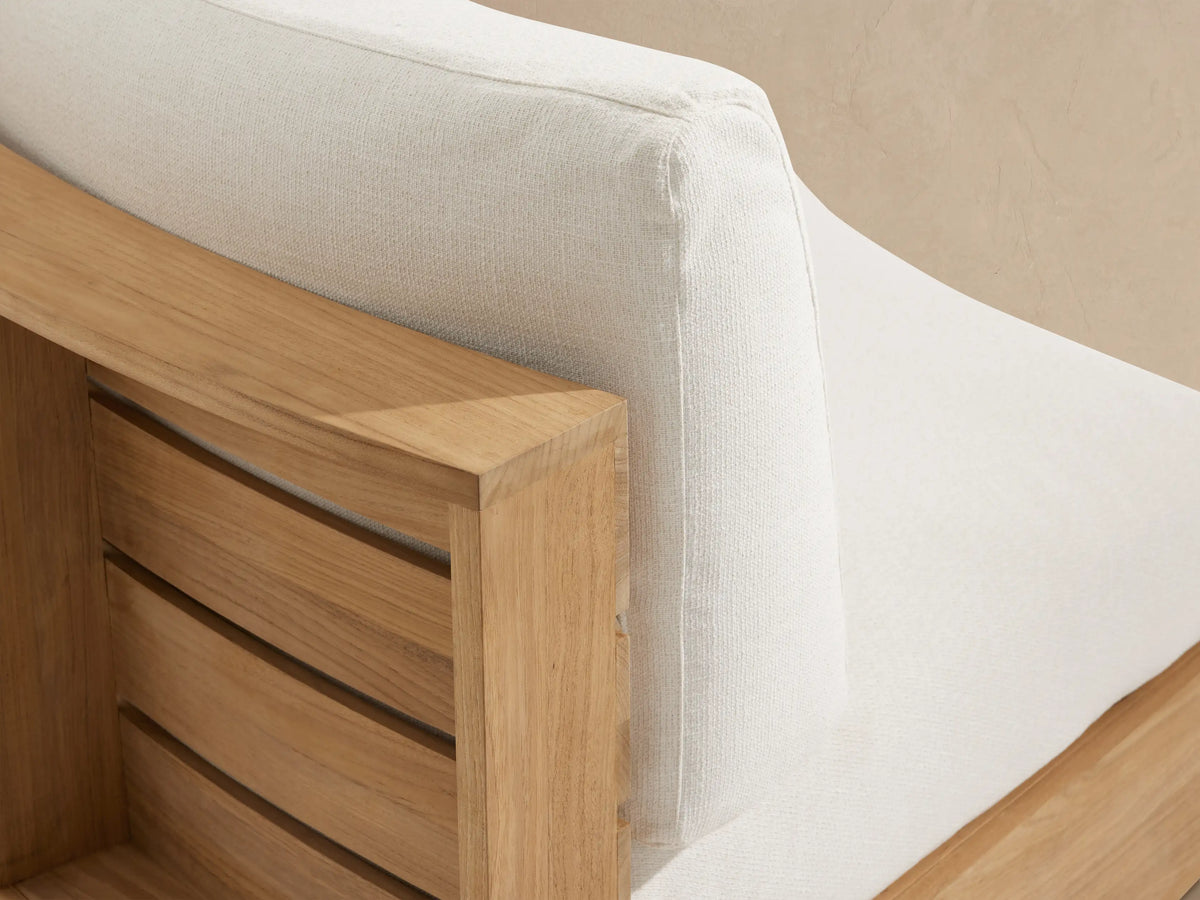 Bal Harbour Outdoor Curved Sofa: light teak wood base, white cushions, curving right on a textured tiled floor.