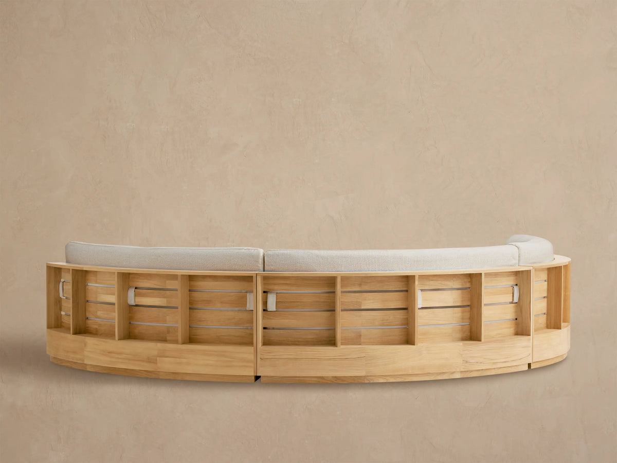 Close-up of Bal Harbour Outdoor Curved Sectional. Light wood armrest & textured beige fabric back cushion are visible.