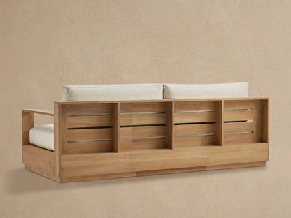 Close-up of Bal Harbour Outdoor Teak Sofa's natural teak wood right armrest and textured cream seat cushion.