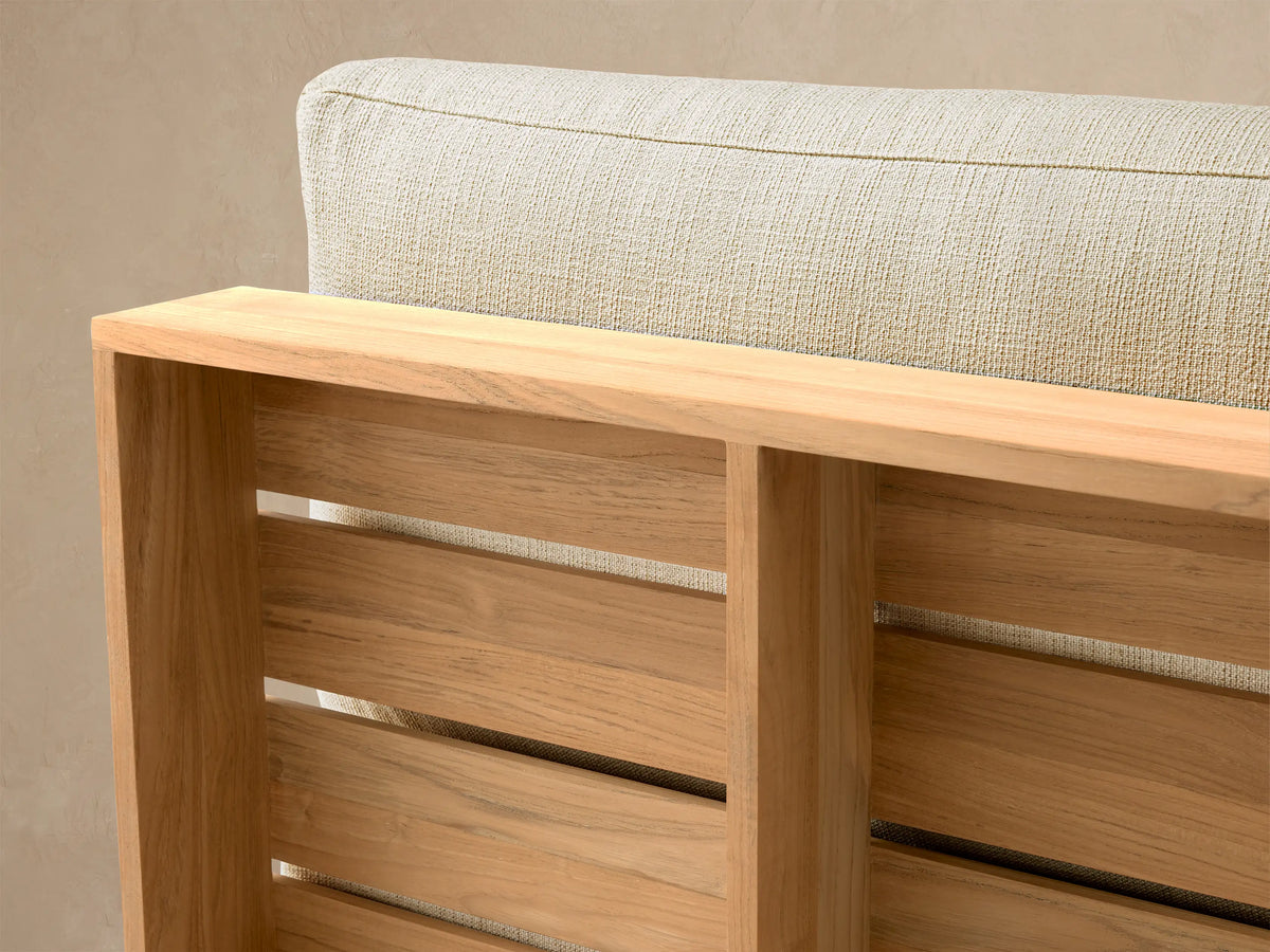 Bal Harbour Outdoor Teak Armless Chair with golden teak base and light beige fabric seat/back cushions, front view.