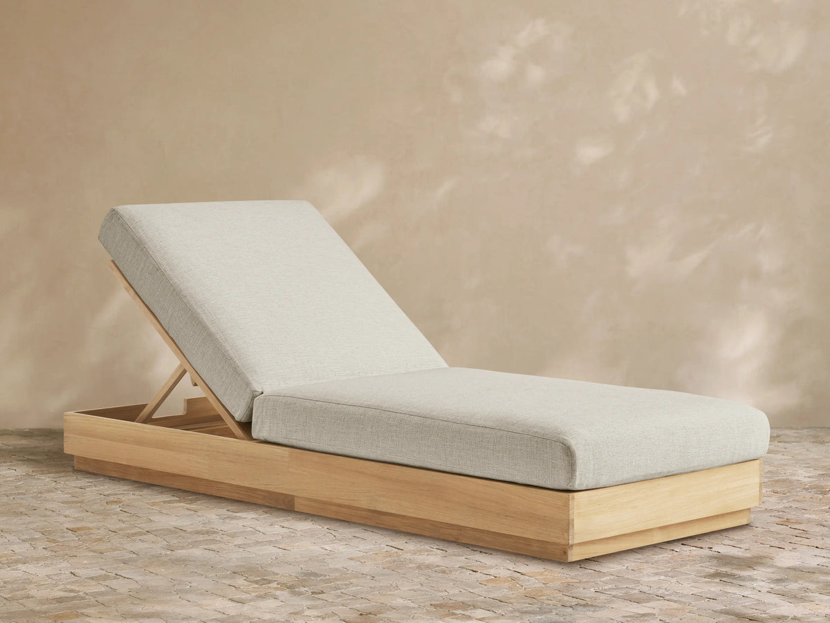 Bal Harbour Outdoor Teak Chaise, light gray cushion on natural teak base, backrest inclined, on stone patio.