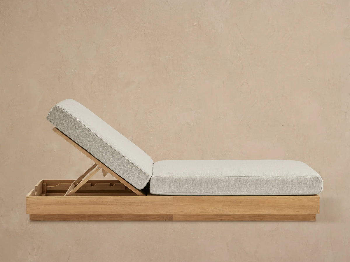 Bal Harbour Outdoor Teak Chaise, light gray cushion on natural teak base, backrest inclined, on stone patio.
