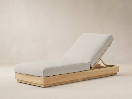 Bal Harbour Outdoor Teak Chaise, light gray cushion on natural teak base, backrest inclined, on stone patio.