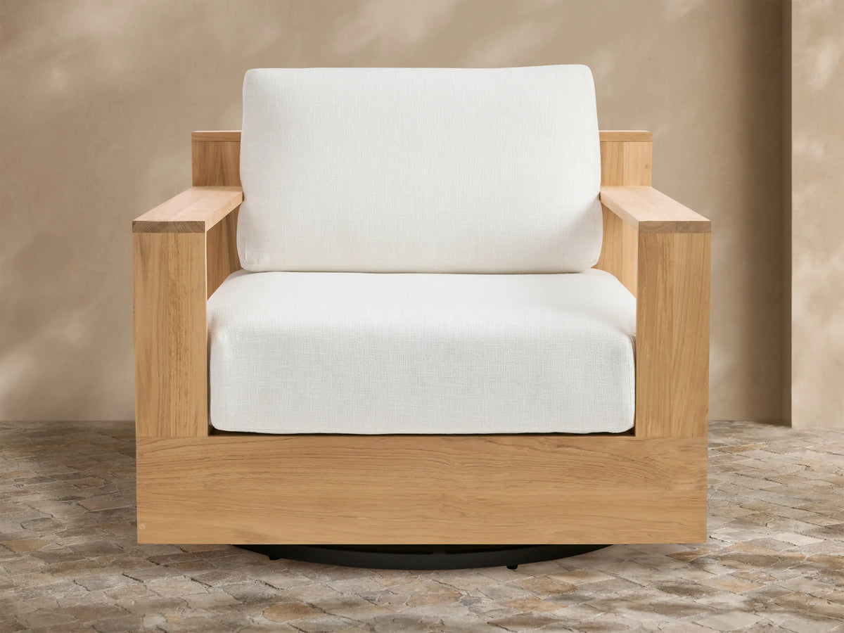 Bal Harbour Outdoor Teak Swivel Chair: Natural teak frame, white seat and back cushions, black swivel base on stone floor.