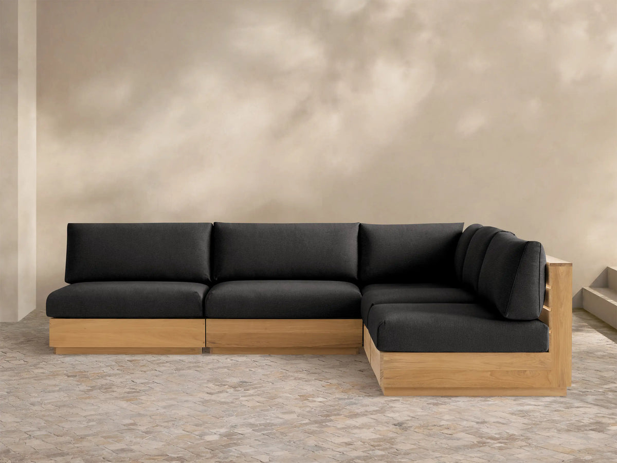 Bal Harbour L-shaped outdoor sectional with natural teak wood base and charcoal gray cushions on a light-colored patio.