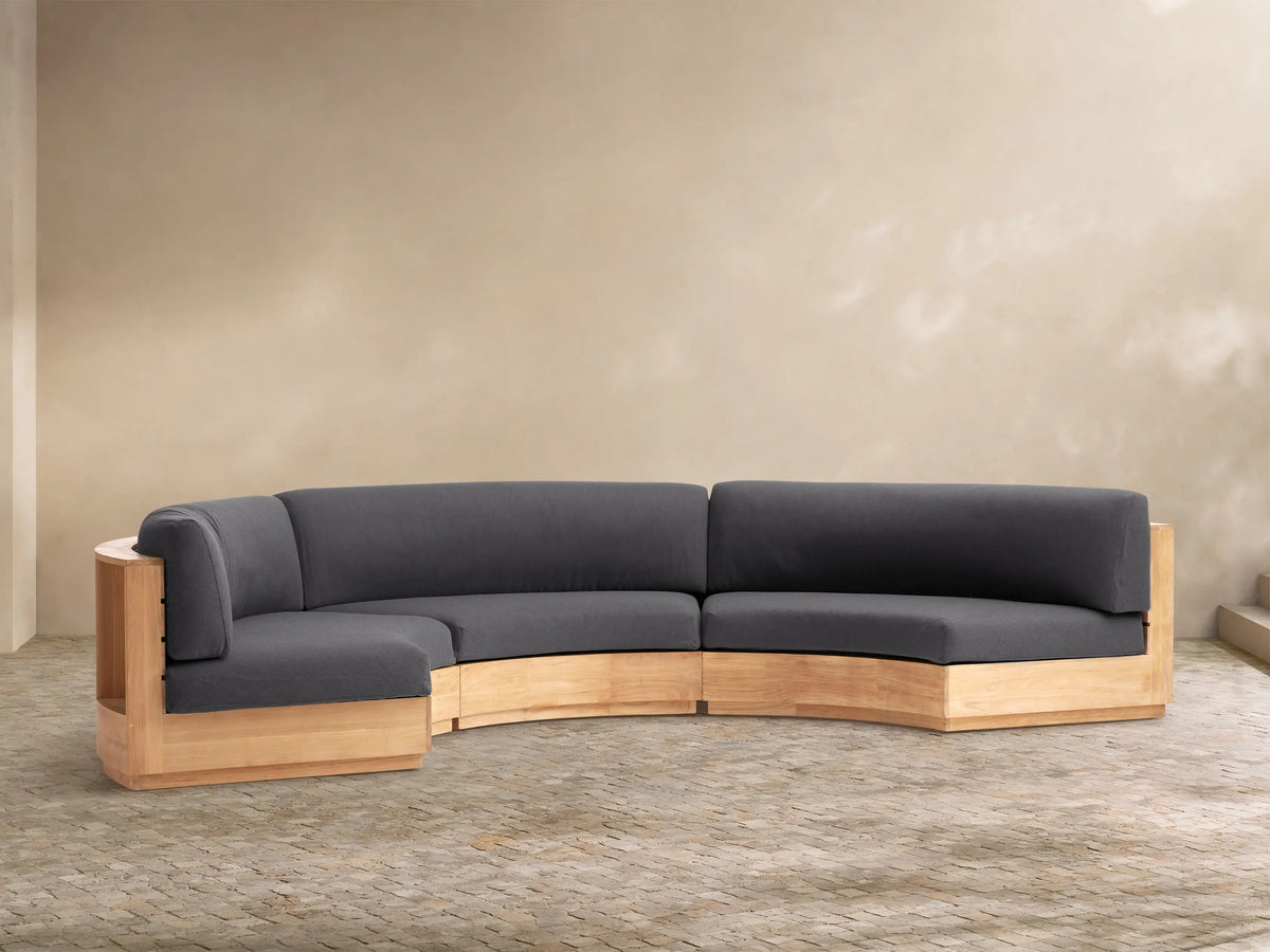 Bal Harbour curved 3-piece outdoor sectional with charcoal cushions and a natural wood frame, on a stone patio.