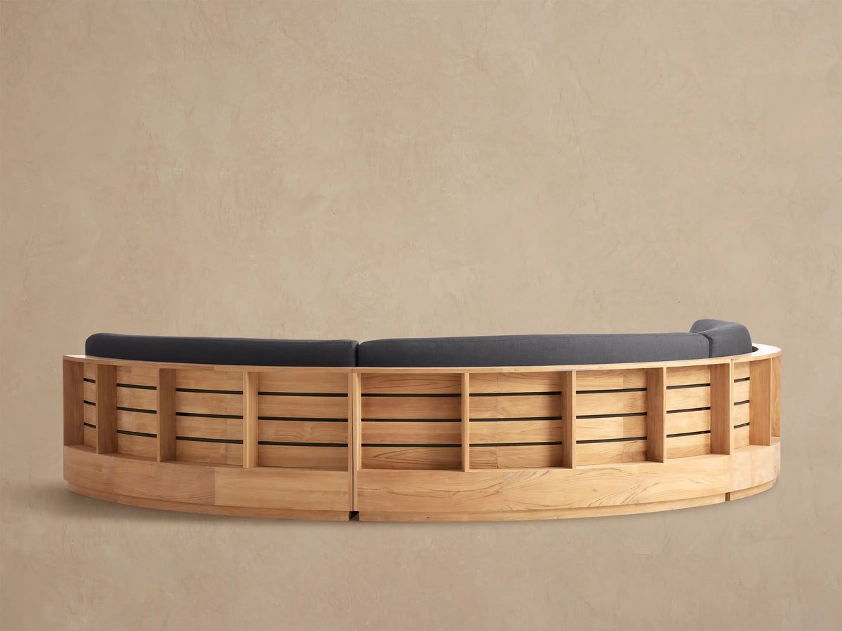 Close-up of Bal Harbour Outdoor Curved Sectional's dark gray back cushion and light brown slatted wooden frame.