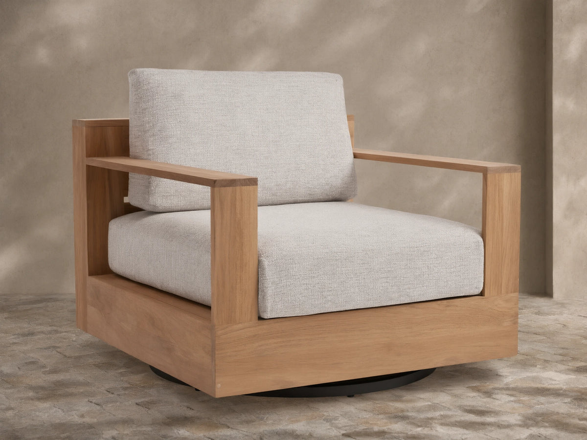 Bal Harbour Outdoor Teak Swivel Chair with natural golden-brown teak frame, light gray cushions, and black swivel base on a patio.