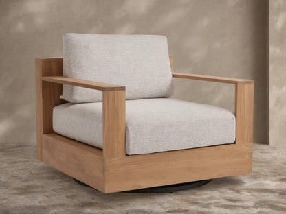 Bal Harbour Outdoor Teak Swivel Chair with natural golden-brown teak frame, light gray cushions, and black swivel base on a patio.