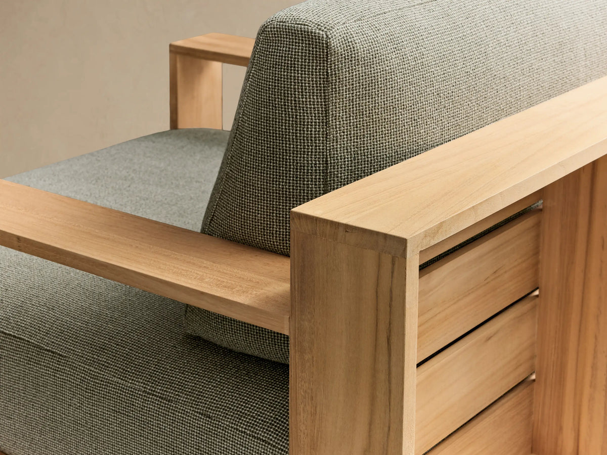 Front view of the Bal Harbour Outdoor Teak Swivel Chair, featuring a natural teak frame and light grey upholstered cushions.