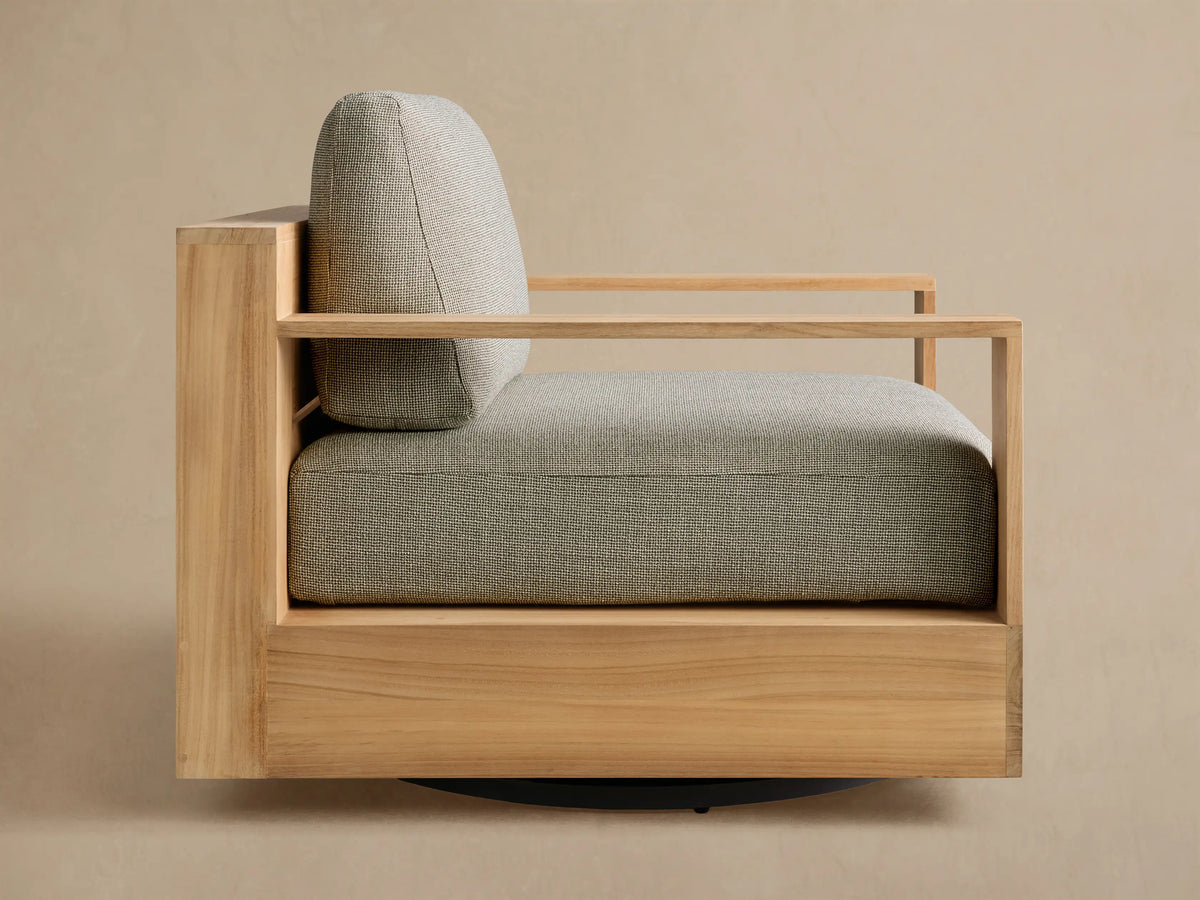 Side view of the natural teak Bal Harbour Outdoor Teak Swivel Chair with light green-gray textured cushions and slatted wooden frame.
