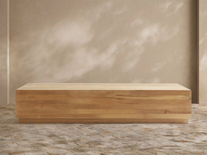 Bal Harbour Outdoor Teak Coffee Table: Rectangular light golden-brown teak table with slatted top on a stone floor, natural light.