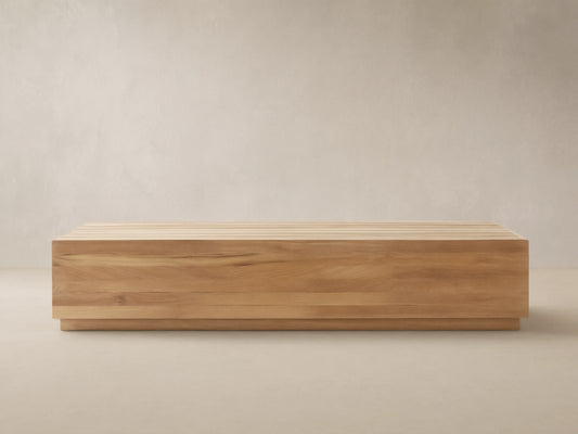 Bal Harbour Outdoor Teak Coffee Table: Rectangular light golden-brown teak table with slatted top on a stone floor, natural light.