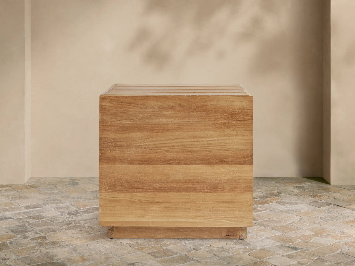 Bal Harbour Outdoor Teak End Table, cube-shaped, natural golden wood grain, slatted top, on stone patio.