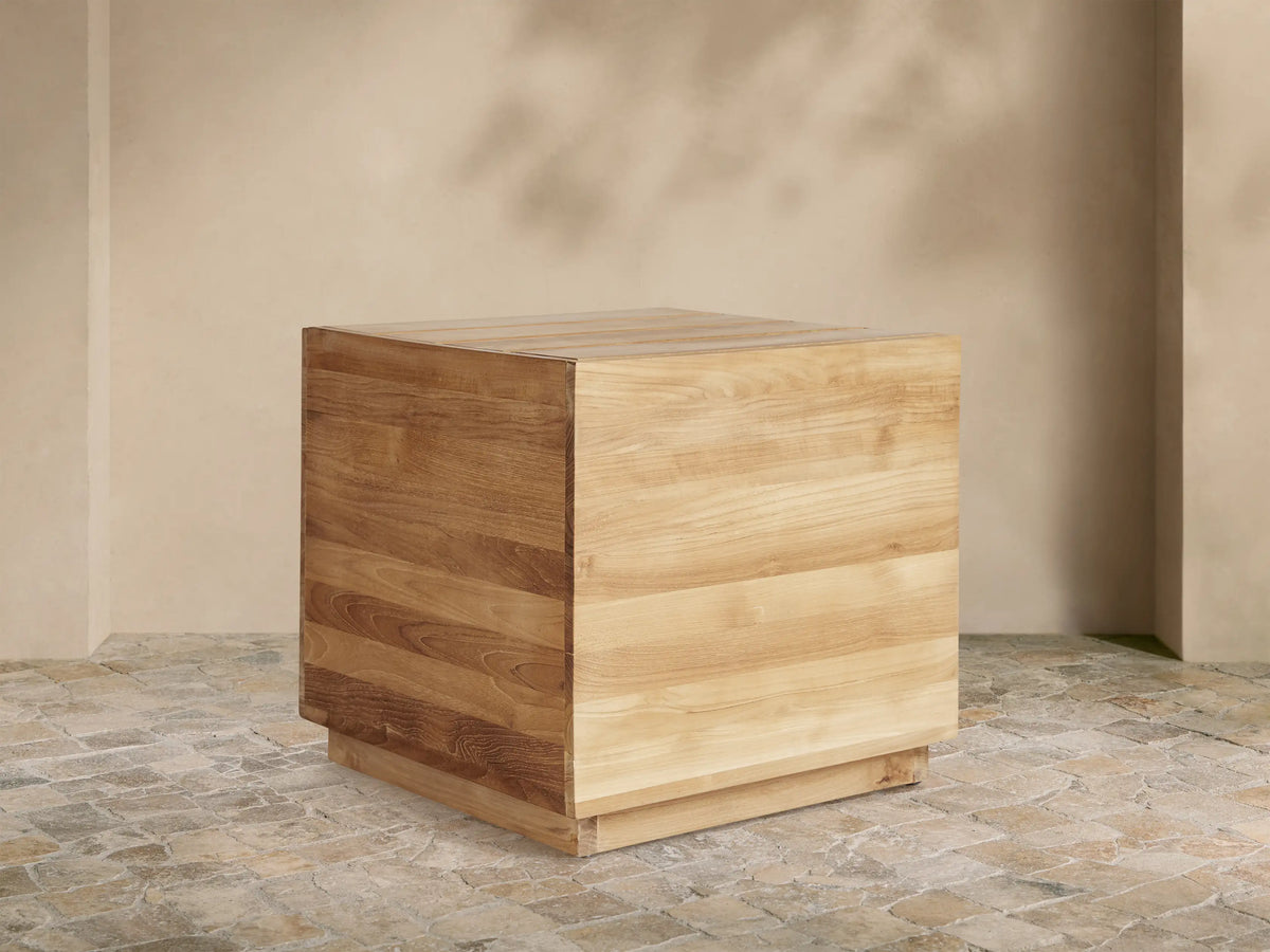 Bal Harbour Outdoor Teak End Table, cube-shaped, natural golden wood grain, slatted top, on stone patio.