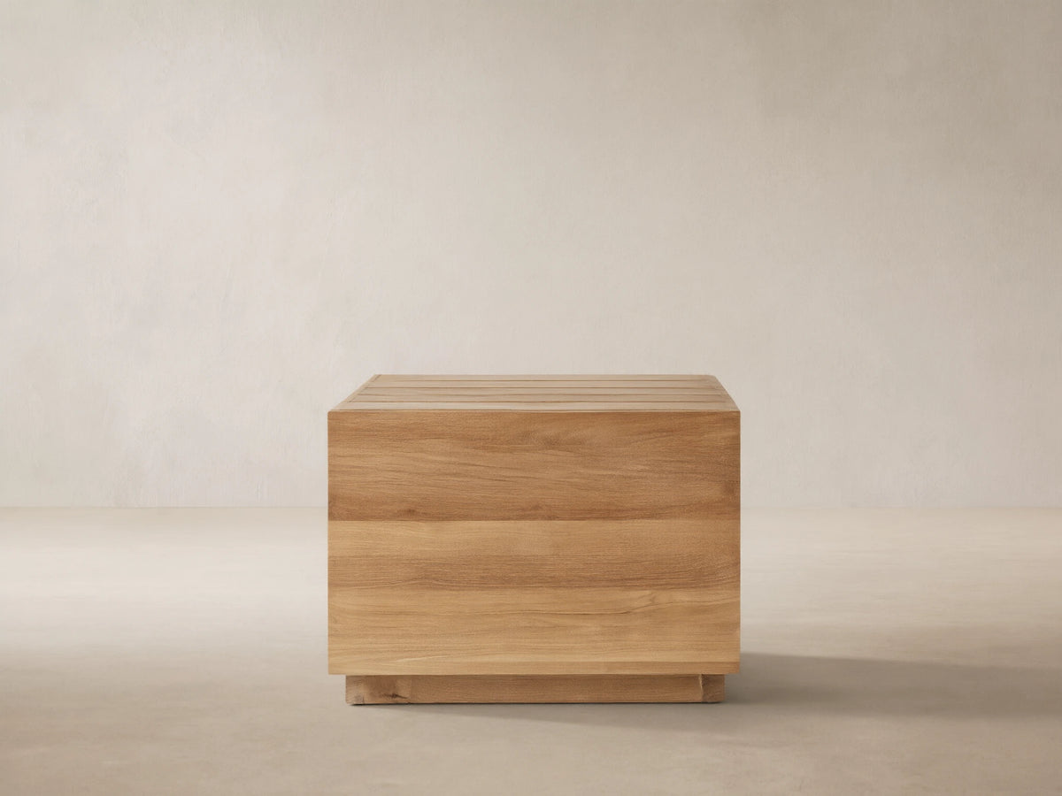 Bal Harbour Outdoor Teak End Table, cube-shaped, natural golden wood grain, slatted top, on stone patio.