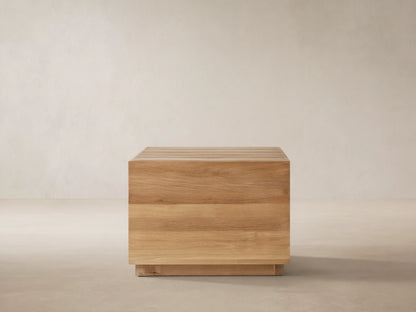 Bal Harbour Outdoor Teak End Table, cube-shaped, natural golden wood grain, slatted top, on stone patio.