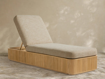 Beaumont Outdoor Teak Chaise with light beige cushions, angled backrest, and slatted teak wood base on a patterned floor.