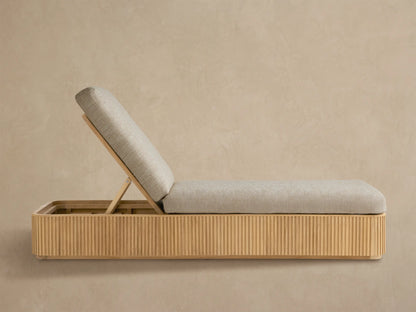 Beaumont Outdoor Teak Chaise with light beige cushions, angled backrest, and slatted teak wood base on a patterned floor.