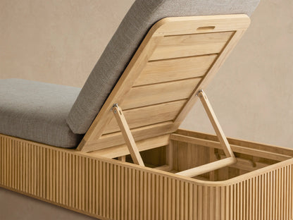 Beaumont Outdoor Teak Chaise, side view. Natural teak frame with fluted details, light grey cushions, headrest elevated.
