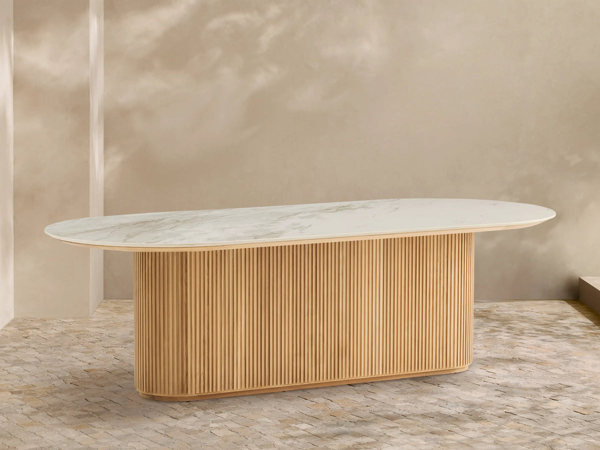 Beaumont Outdoor Teak Dining Table: Oval white marbled top on a natural golden fluted teak wood pedestal base, outdoor patio.