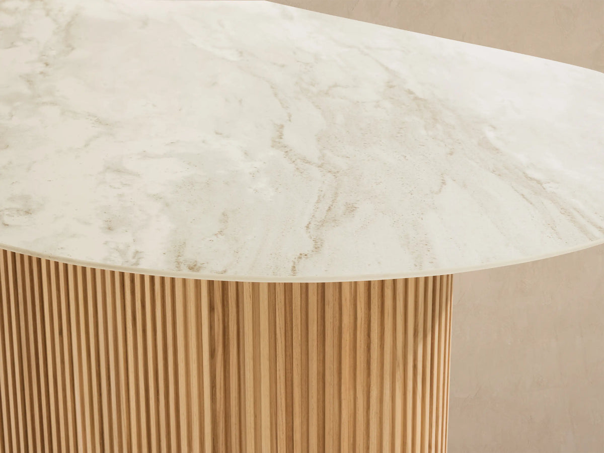 Beaumont Outdoor Teak Dining Table: oval white sintered stone top, fluted natural teak base, angled view on tiled floor.