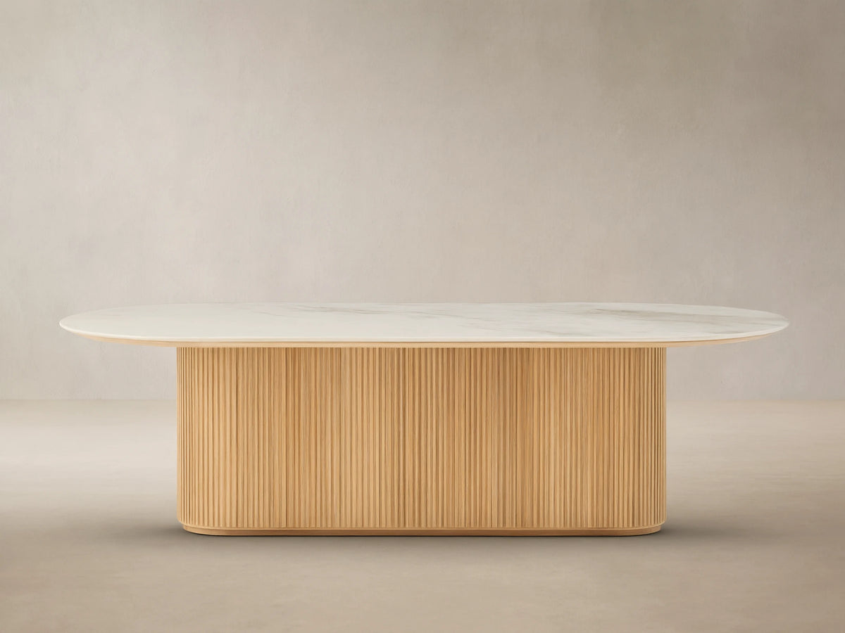 Beaumont Outdoor Teak Dining Table: Oval white marbled top on a natural golden fluted teak wood pedestal base, outdoor patio.