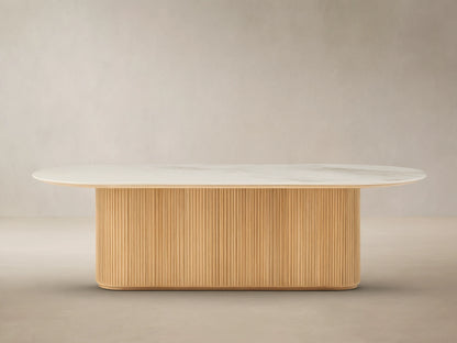 Beaumont Outdoor Teak Dining Table: Oval white marbled top on a natural golden fluted teak wood pedestal base, outdoor patio.