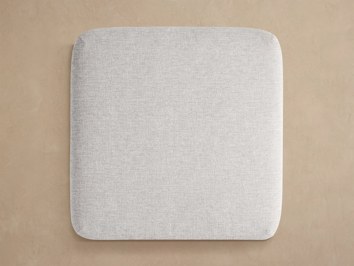 Close-up of Beaumont Outdoor Aluminum Ottoman. Light gray textured fabric cushion sits on a dark fluted aluminum base.