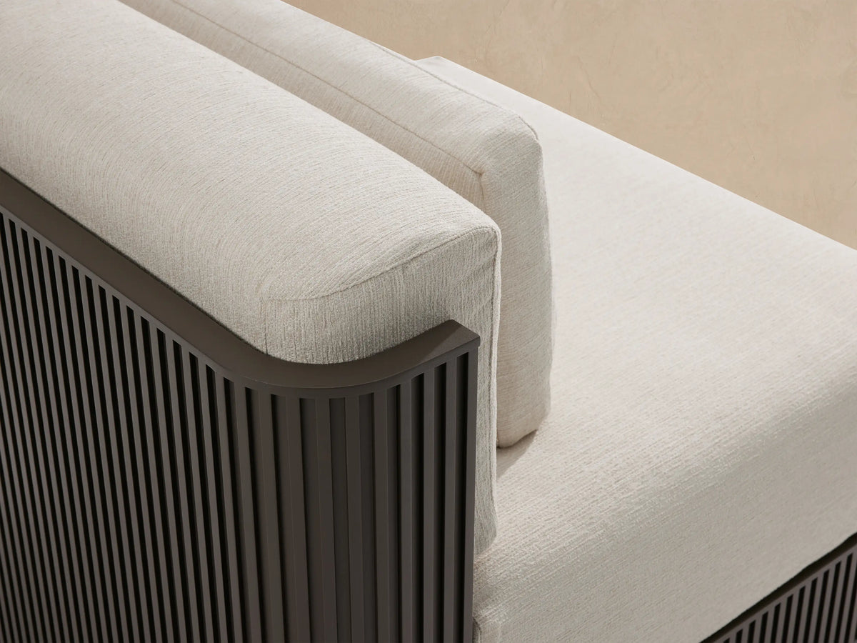 Front view of Beaumont Outdoor Aluminum Lounge Chair with thick light cream cushions & dark gray slatted base on a patio.