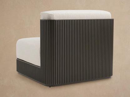 Close-up of Beaumont Outdoor Aluminum Lounge Chair, dark slatted frame, rounded armrest, and light textured cushions.
