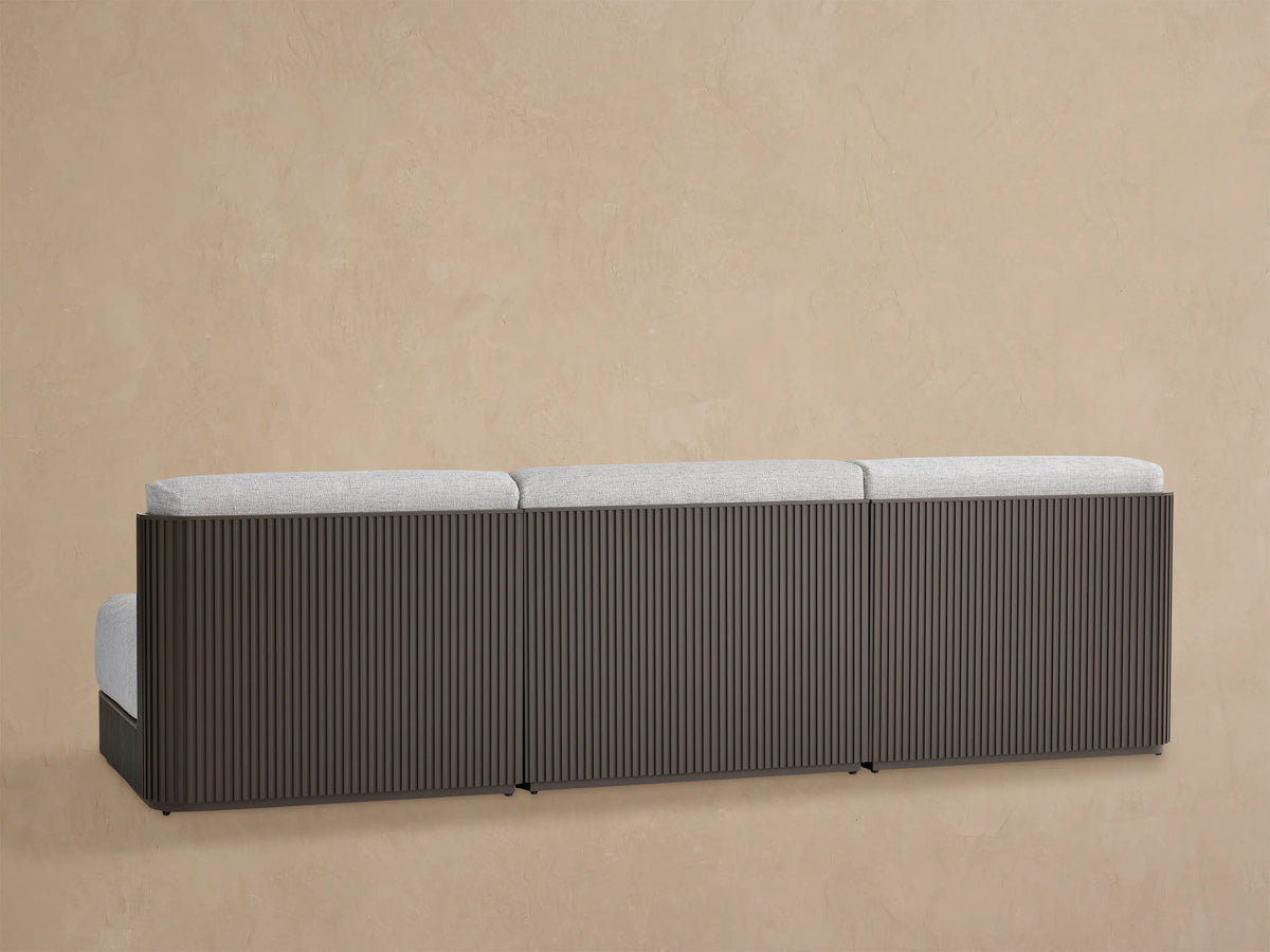 Close-up of Beaumont Modular Sofa. Dark brown aluminum frame with vertical slats, light grey textured seat and back cushions.